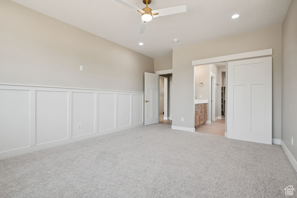 Unfurnished bedroom with light colored carpet, a decorative wall, wainscoting, recessed lighting, and ensuite bathroom