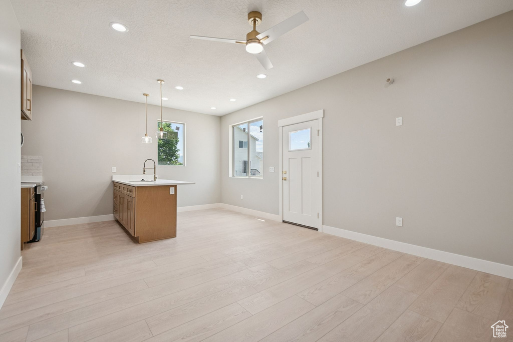 Kitchen featuring a peninsula, light countertops, light wood-type flooring, a ceiling fan, and recessed lighting