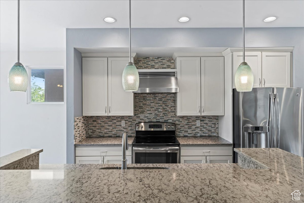 Kitchen with stainless steel appliances, extractor fan, a sink, light stone counters, and recessed lighting