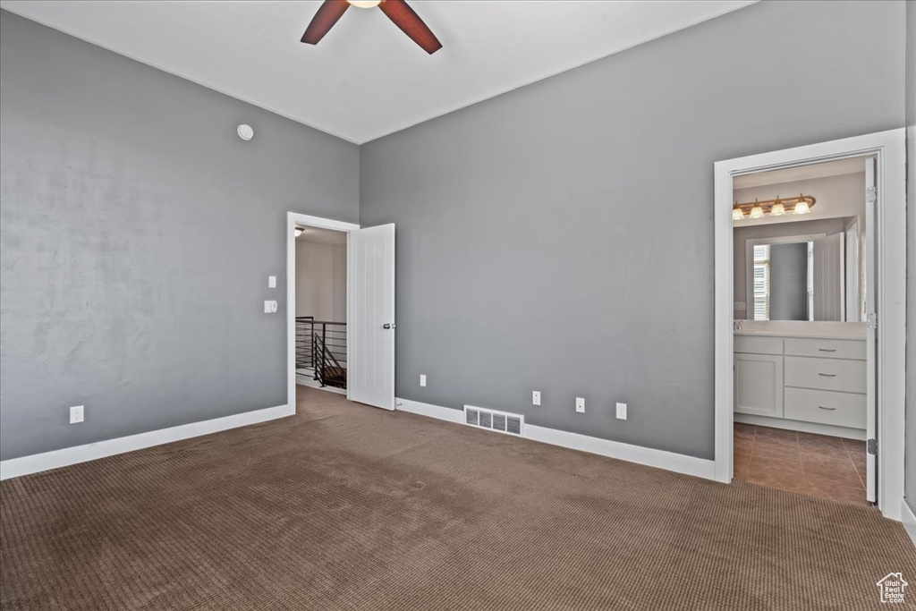 Unfurnished bedroom featuring carpet, baseboards, ceiling fan, and ensuite bathroom