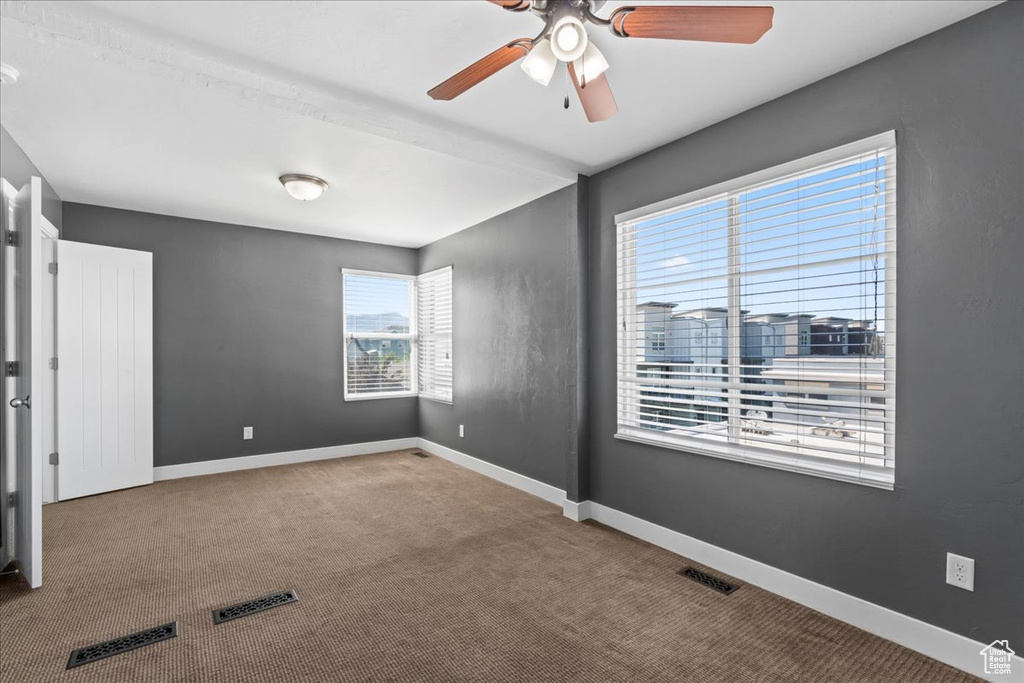 Spare room featuring carpet flooring, baseboards, and ceiling fan