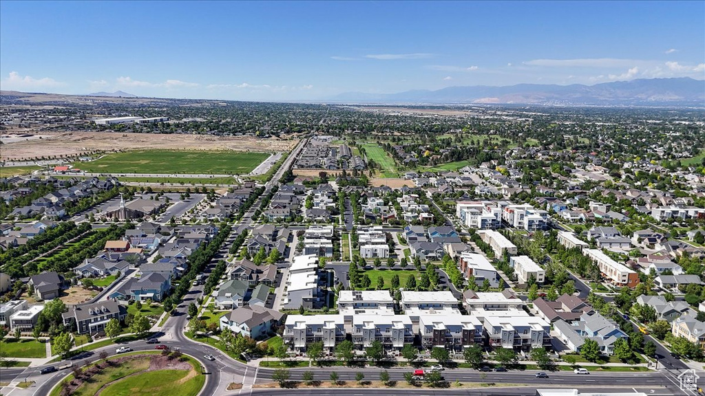 Aerial view of property and surrounding area featuring a mountainous background and nearby suburban area