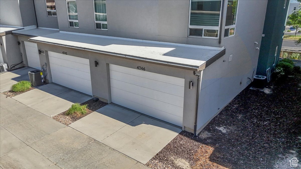 Garage featuring central air condition unit and driveway