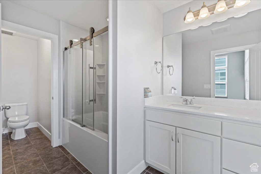 Full bathroom with toilet, vanity, shower / bath combination with glass door, and baseboards