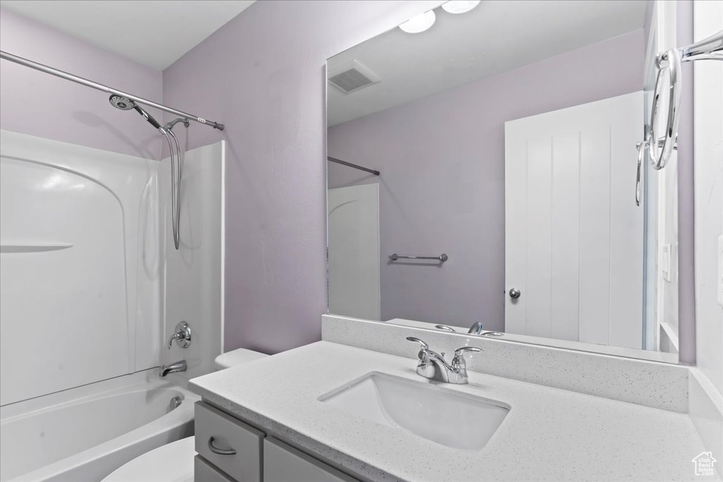 Bathroom with toilet, vanity, and  shower combination