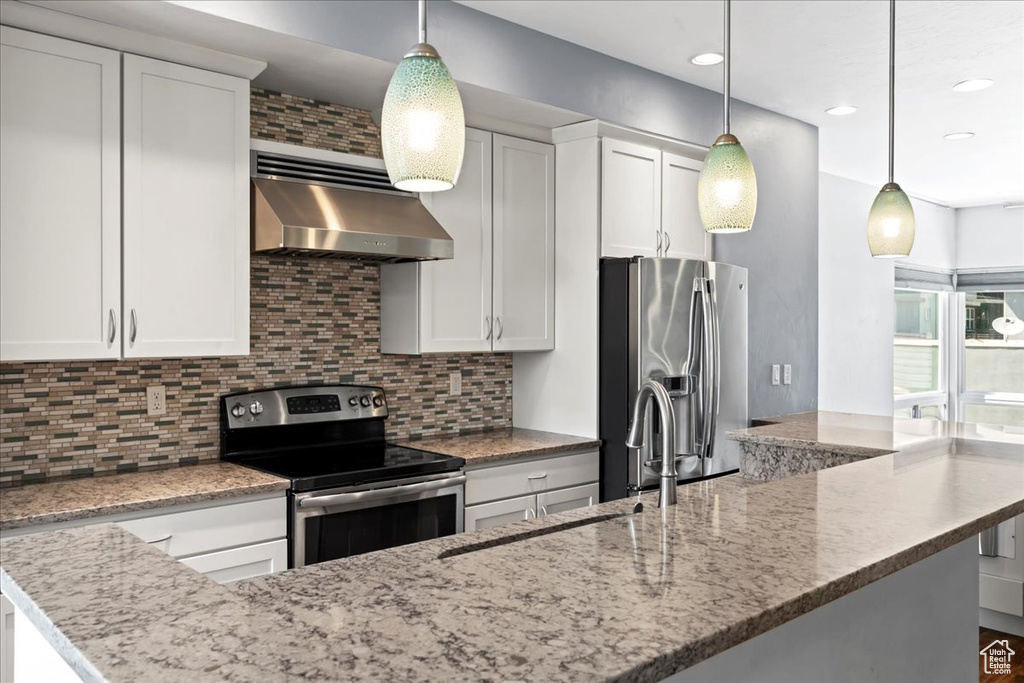 Kitchen with appliances with stainless steel finishes, wall chimney range hood, backsplash, and recessed lighting