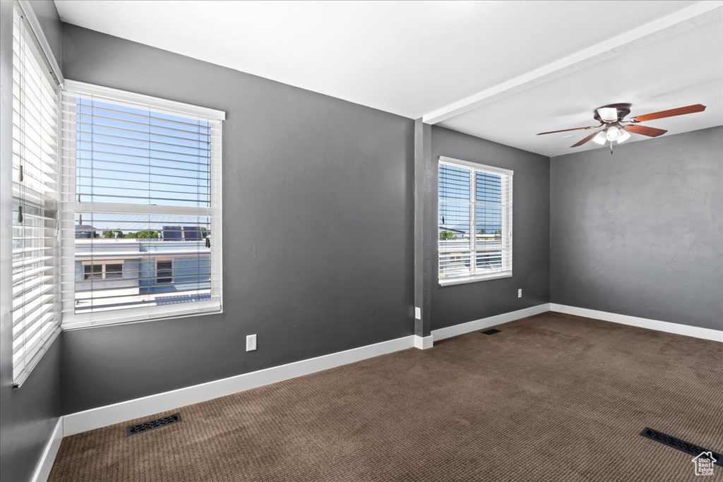 Carpeted spare room with a ceiling fan and baseboards