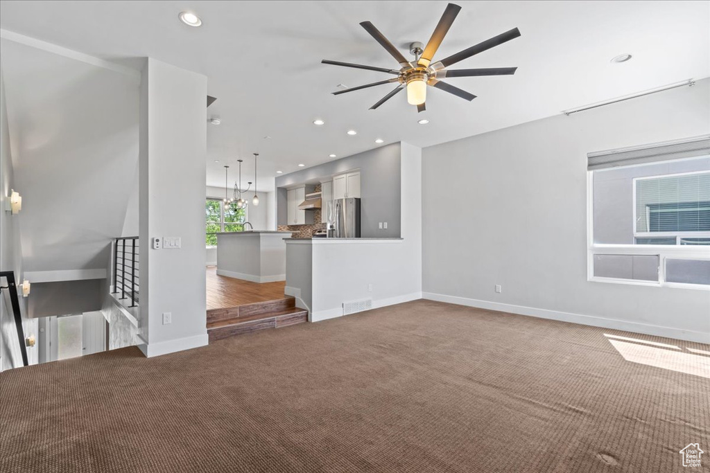 Unfurnished living room with carpet floors, a ceiling fan, baseboards, and recessed lighting