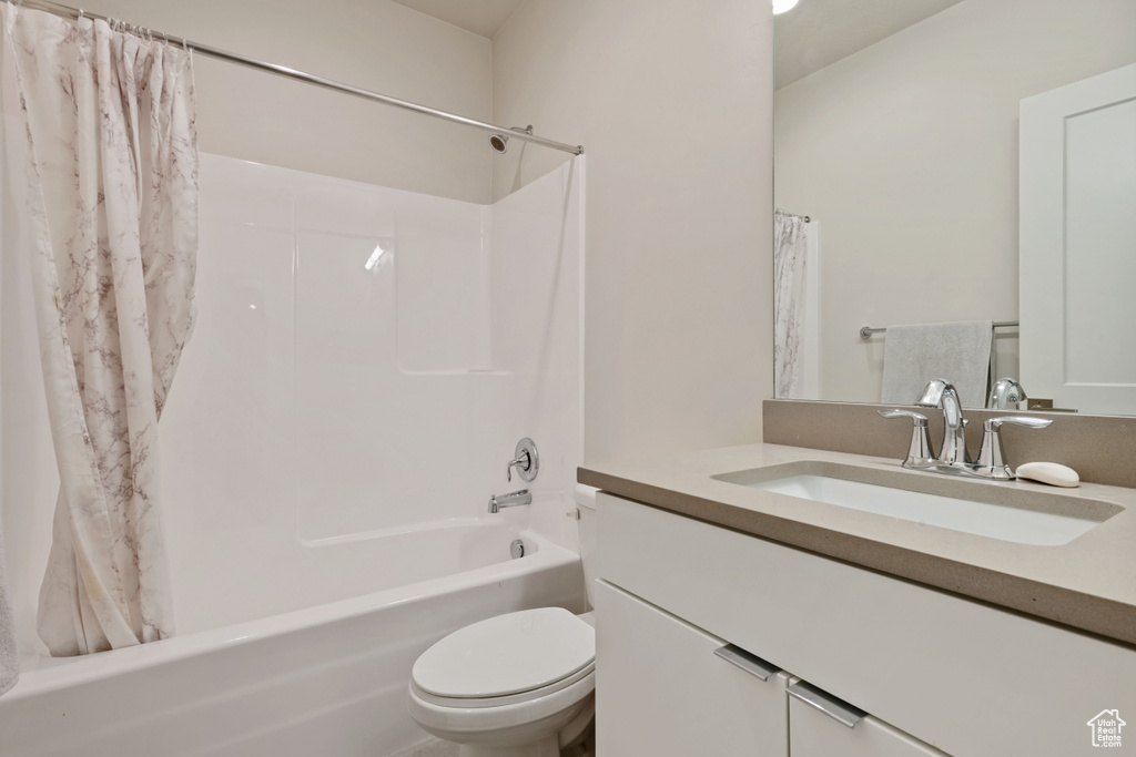 Bathroom with vanity, shower / bath combo with shower curtain, and toilet
