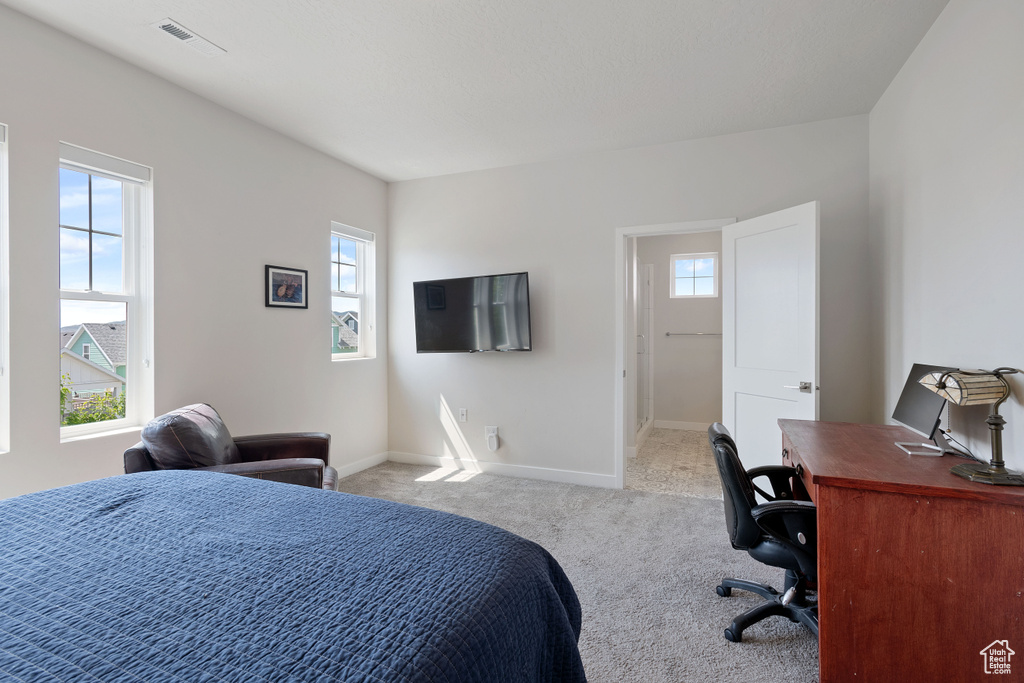 Carpeted bedroom with a desk and baseboards