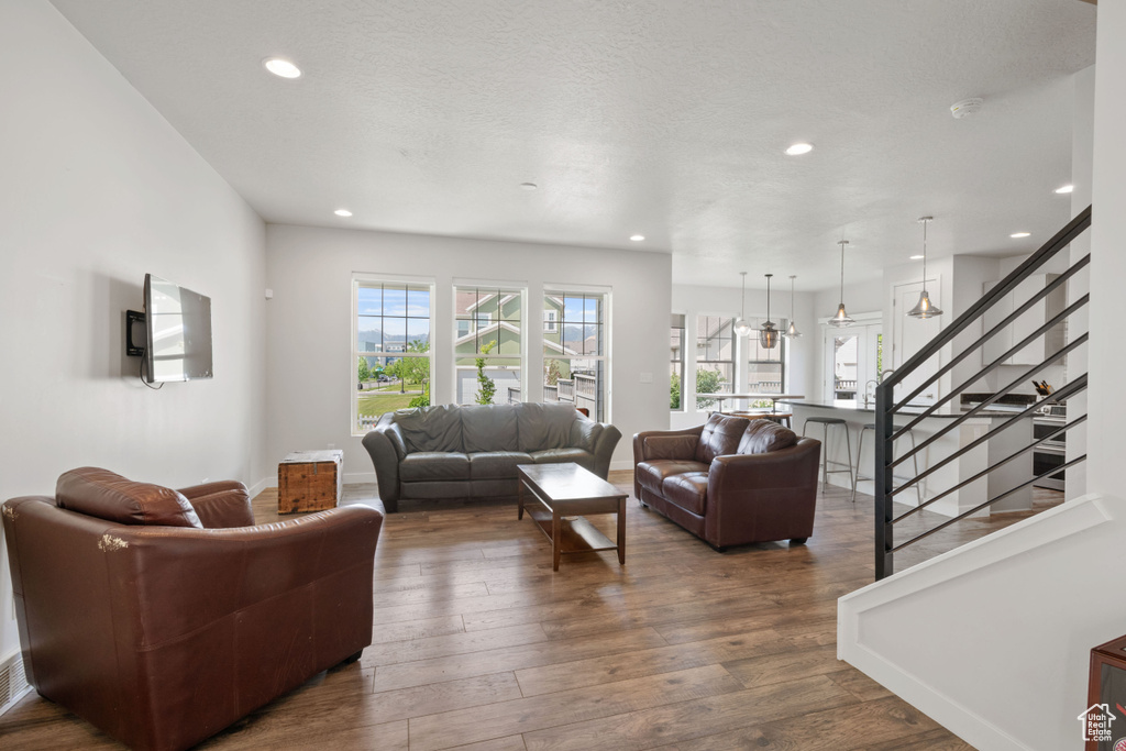 Living room with stairs, recessed lighting, dark wood-style floors, and baseboards