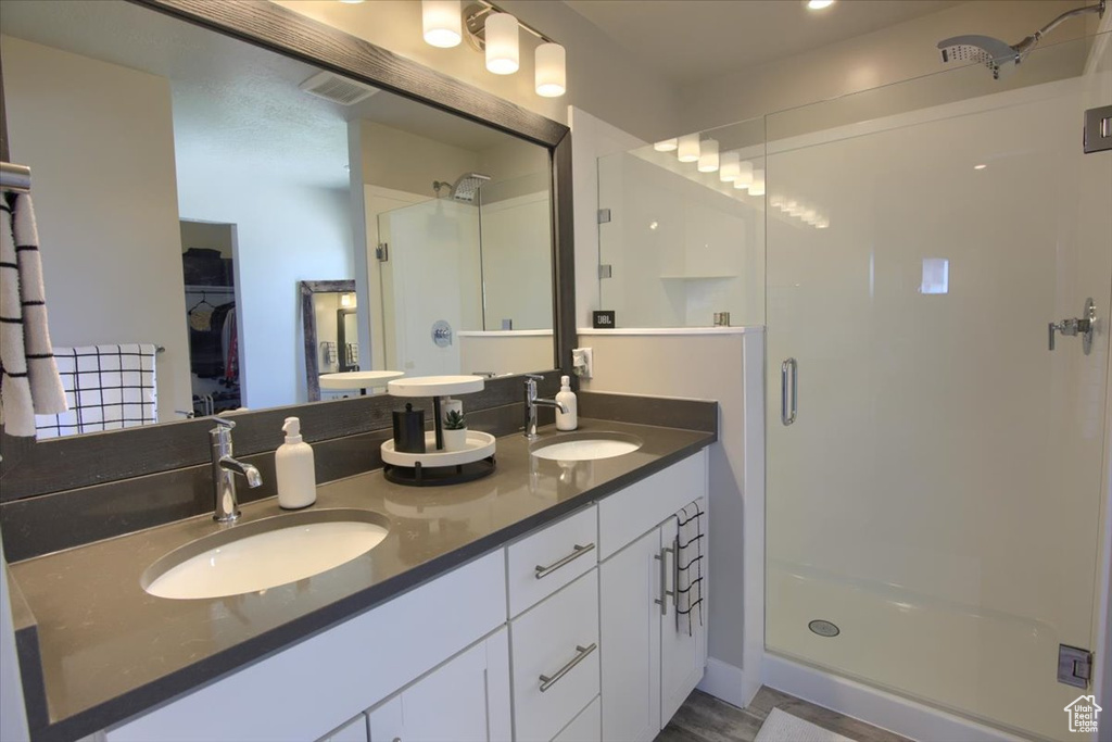Bathroom featuring a stall shower, double vanity, and a spacious closet