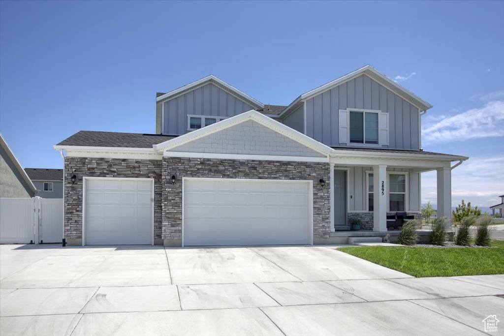 Craftsman inspired home featuring a garage, covered porch, board and batten siding, and driveway