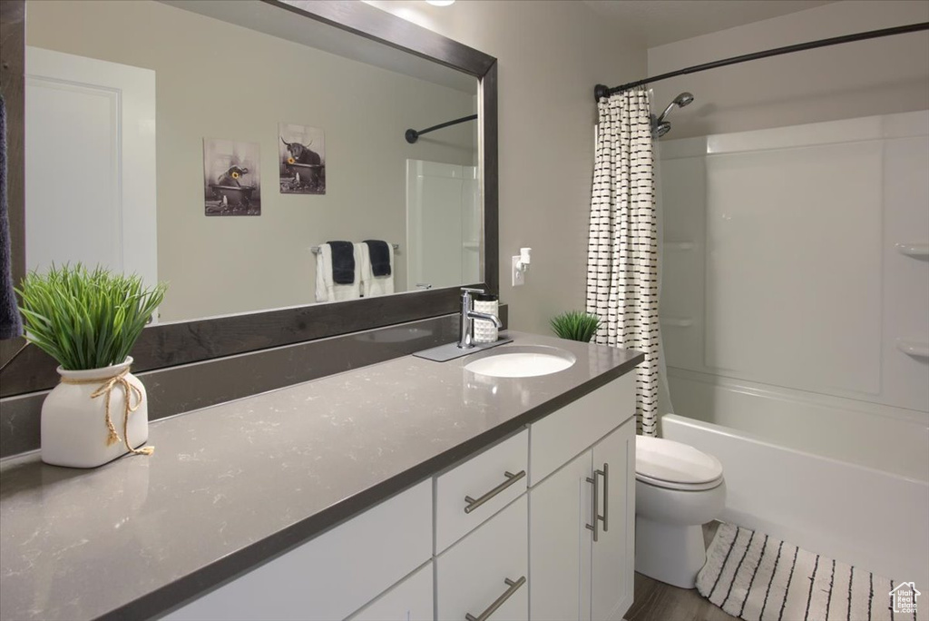 Full bath featuring vanity, toilet, shower / bath combination with curtain, and wood finished floors