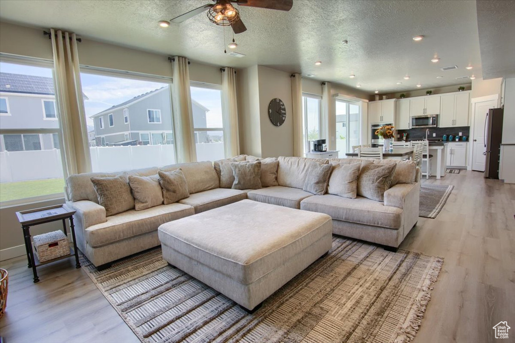Living area with light wood-style flooring, ceiling fan, a textured ceiling, and recessed lighting
