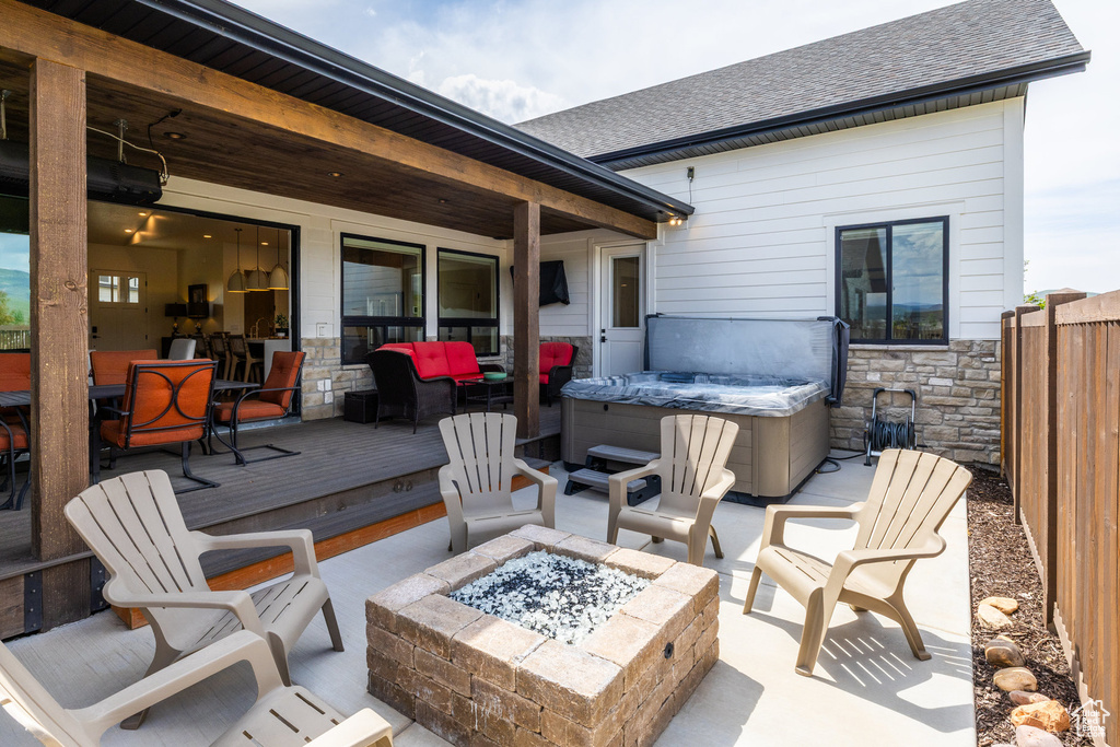 View of patio / terrace with a hot tub, an outdoor fire pit, and a deck