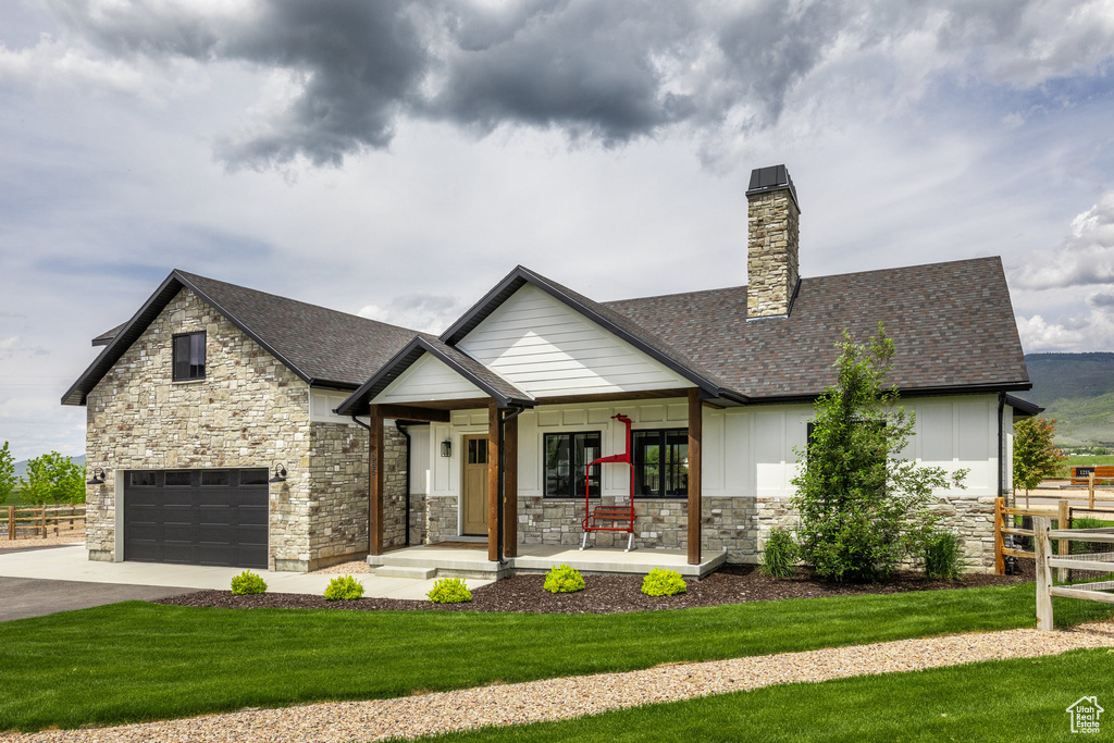 View of front of home featuring a porch, stone siding, roof with shingles, driveway, and board and batten siding