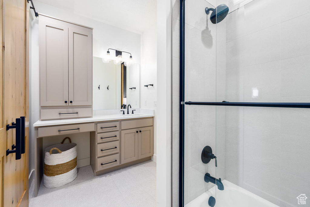 Bathroom featuring vanity and shower / bath combination with glass door
