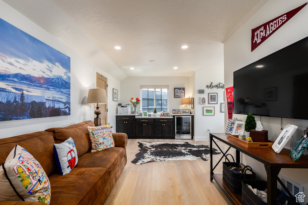 Living room with beverage cooler, light wood-style floors, recessed lighting, and baseboards