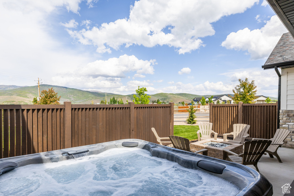 View of patio / terrace with a mountain view, a fire pit, and a hot tub