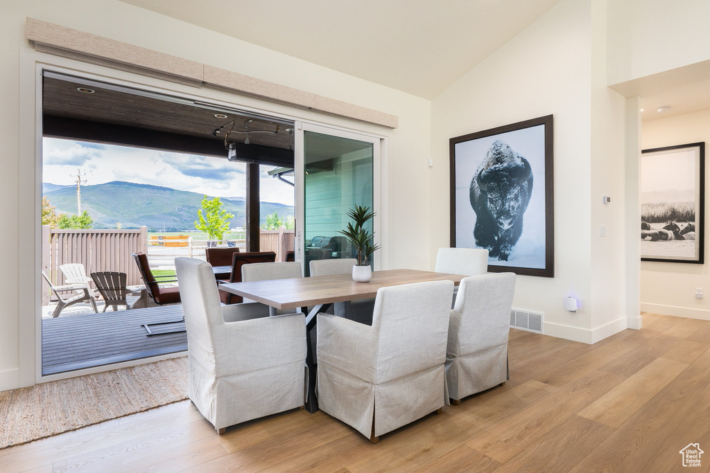 Dining room featuring light wood-style floors, baseboards, lofted ceiling, and a mountain view