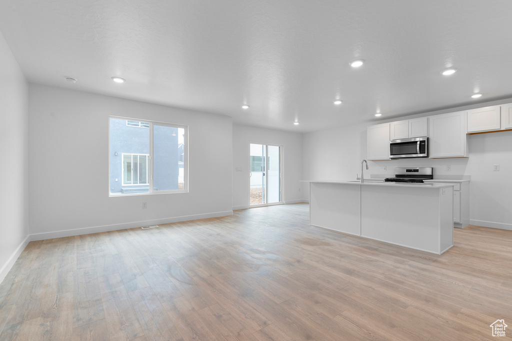 Kitchen featuring appliances with stainless steel finishes, light wood-style floors, recessed lighting, white cabinetry, and baseboards