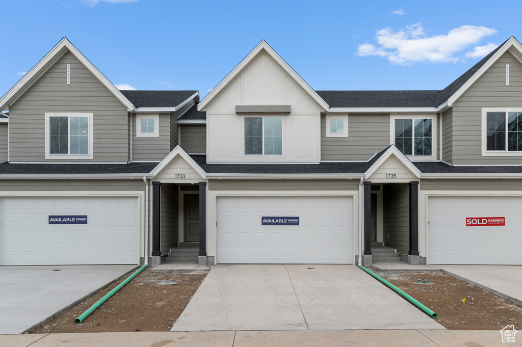 View of property with an attached garage, concrete driveway, and roof with shingles