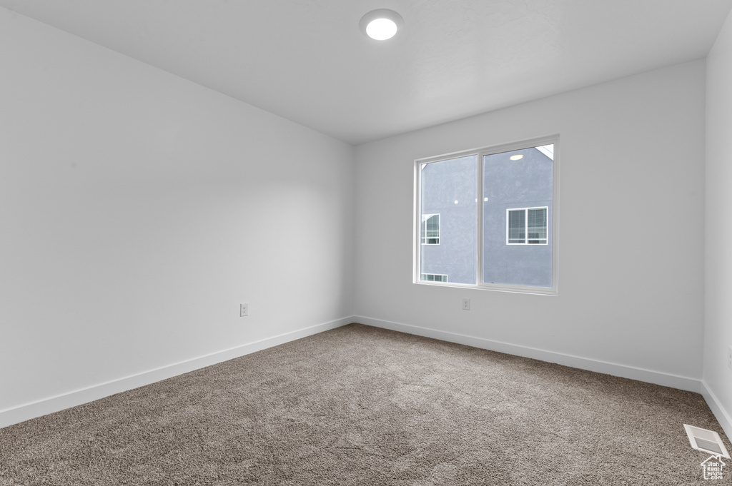 Carpeted spare room featuring baseboards