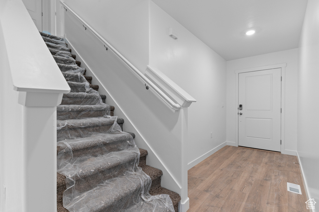Entryway featuring light wood finished floors, baseboards, and stairway