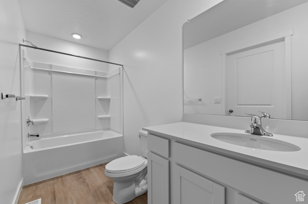 Bathroom with vanity, wood finished floors, toilet, and shower / bathtub combination