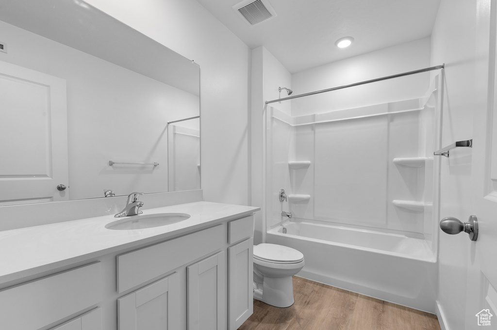 Full bath with vanity, toilet, shower / bath combination, and wood finished floors