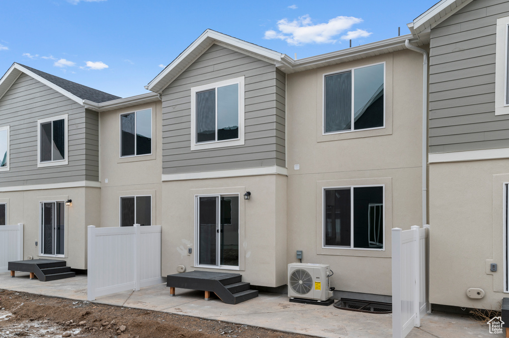 Rear view of house featuring a cooling unit, stucco siding, and a patio area