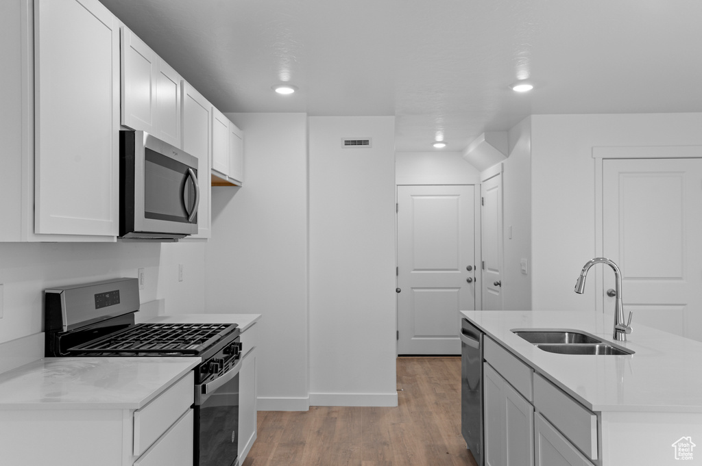 Kitchen featuring appliances with stainless steel finishes, a sink, light wood-type flooring, recessed lighting, and baseboards