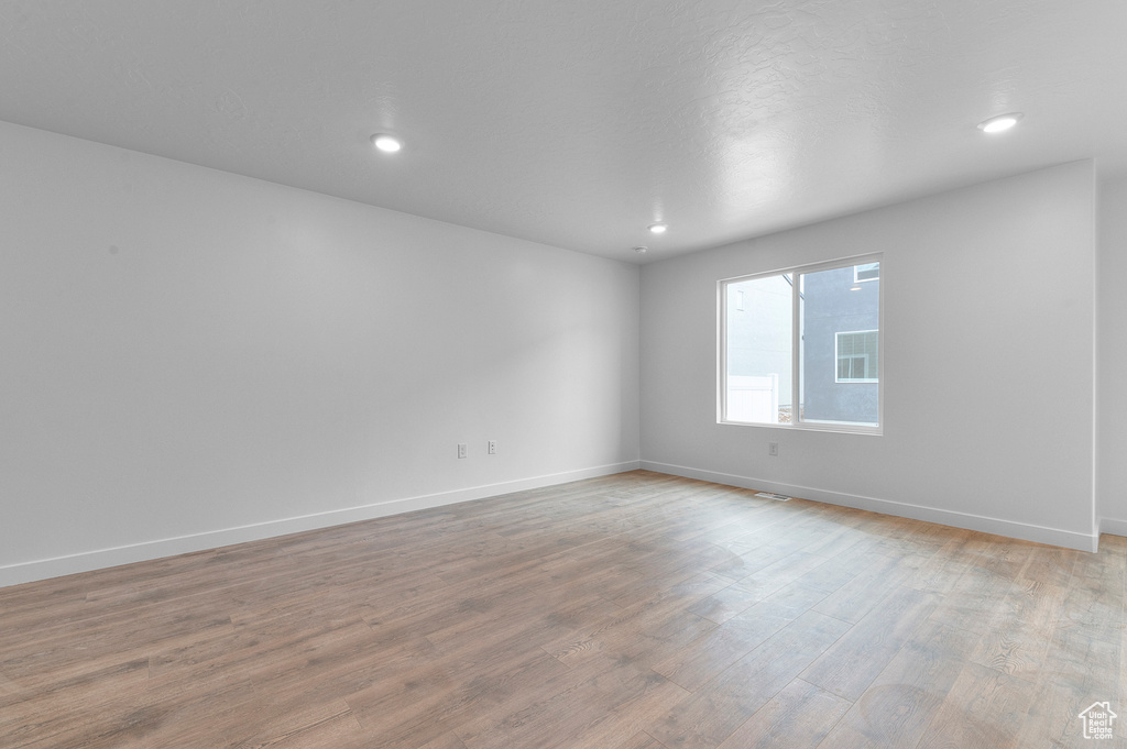 Empty room featuring light wood finished floors, baseboards, and recessed lighting