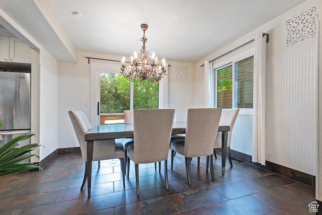 Dining space featuring healthy amount of natural light, a chandelier, and baseboards