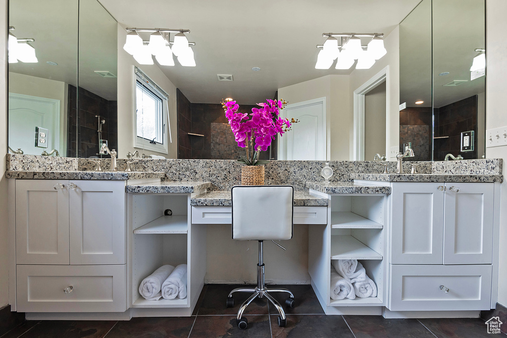 Full bath featuring vanity, tile patterned flooring, and a tile shower