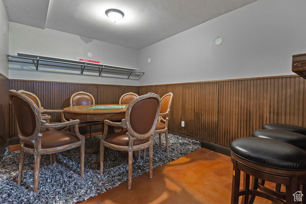 Dining room with wainscoting, finished concrete flooring, and wooden walls