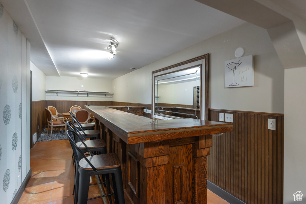 Indoor dry bar featuring a wainscoted wall and wood walls
