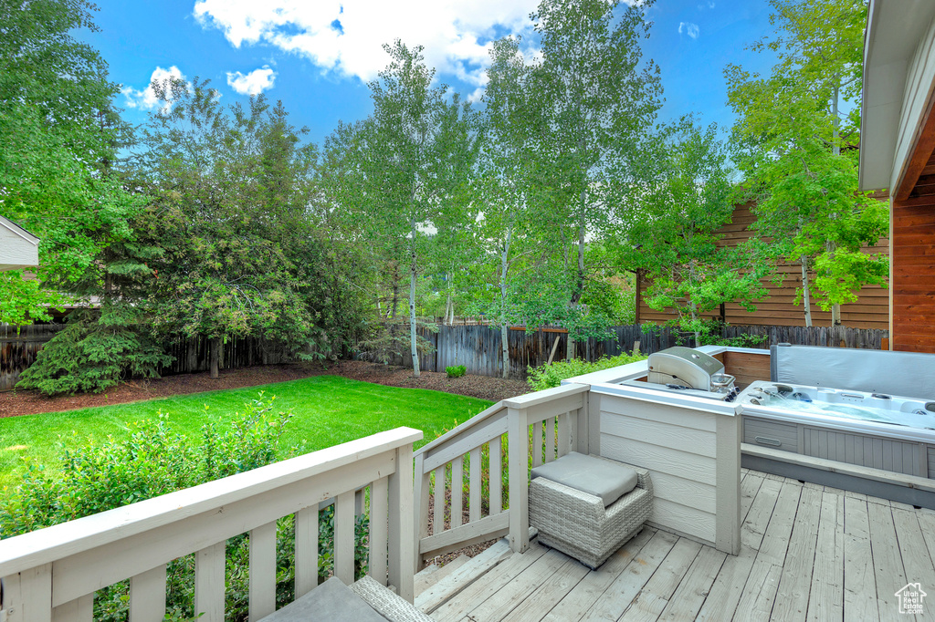 Wooden deck with a hot tub and a grill