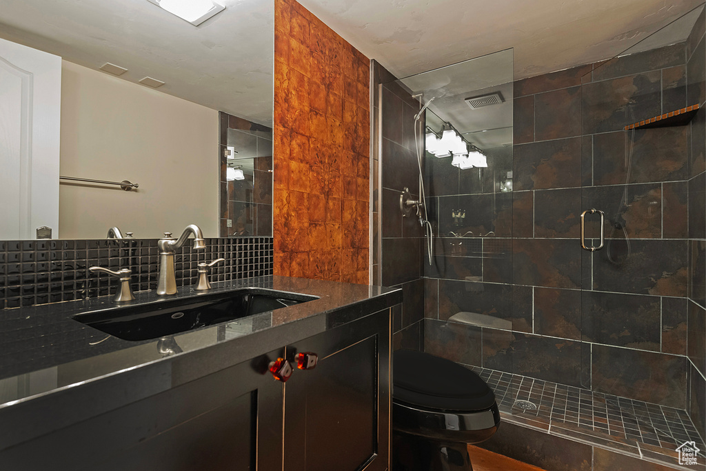 Full bath featuring a shower stall, toilet, vanity, and backsplash