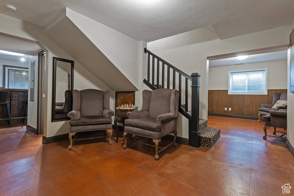 Living area featuring a wainscoted wall, stairway, and wooden walls