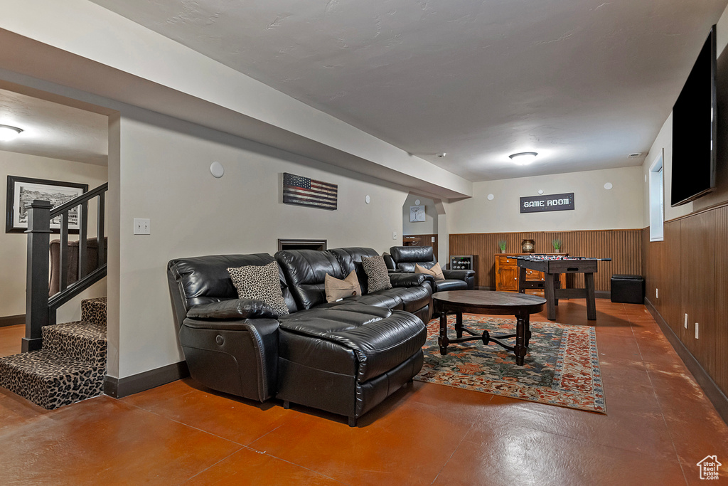 Living area with concrete flooring, stairs, wainscoting, and wood walls