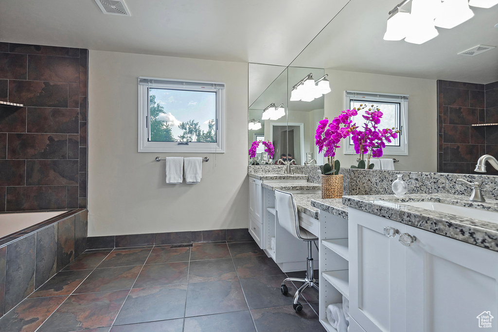 Full bathroom with plenty of natural light, double vanity, and baseboards