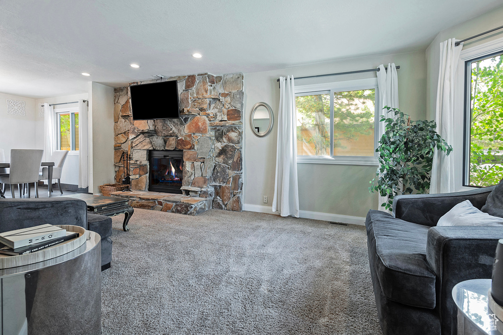 Living room with carpet, baseboards, a stone fireplace, and recessed lighting
