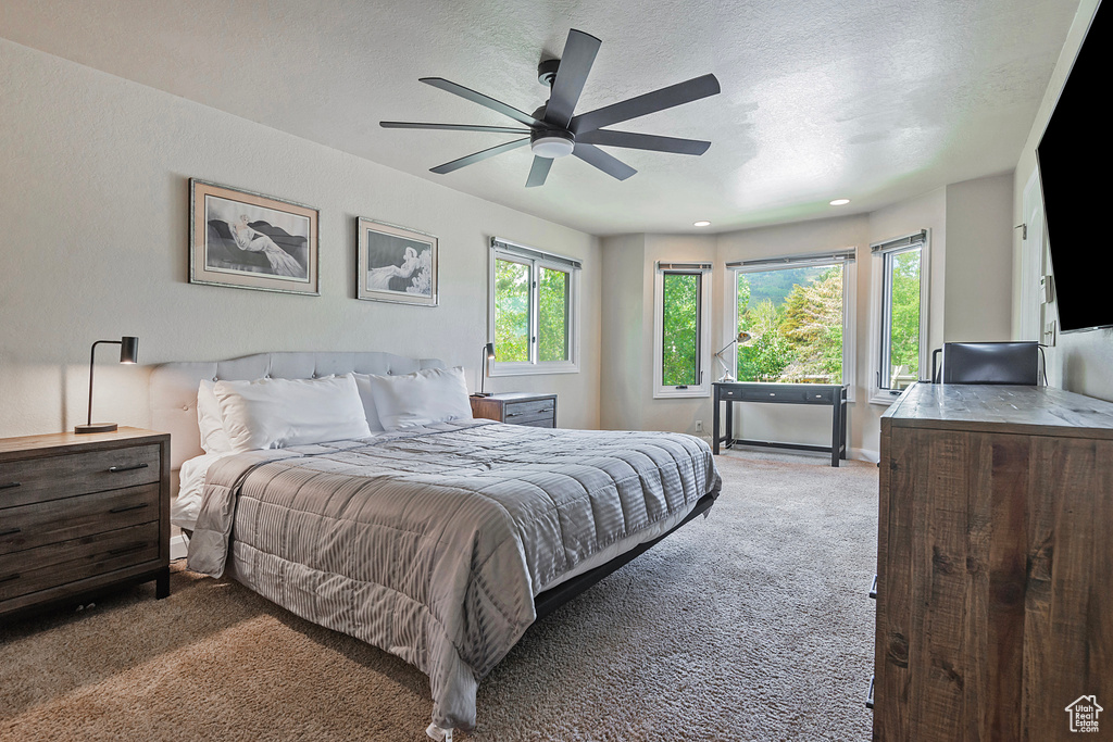 Bedroom with carpet floors, a textured ceiling, and ceiling fan