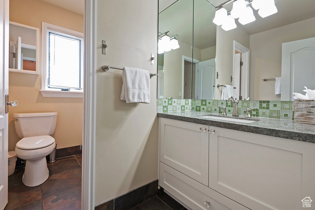 Bathroom with tasteful backsplash, vanity, toilet, and baseboards