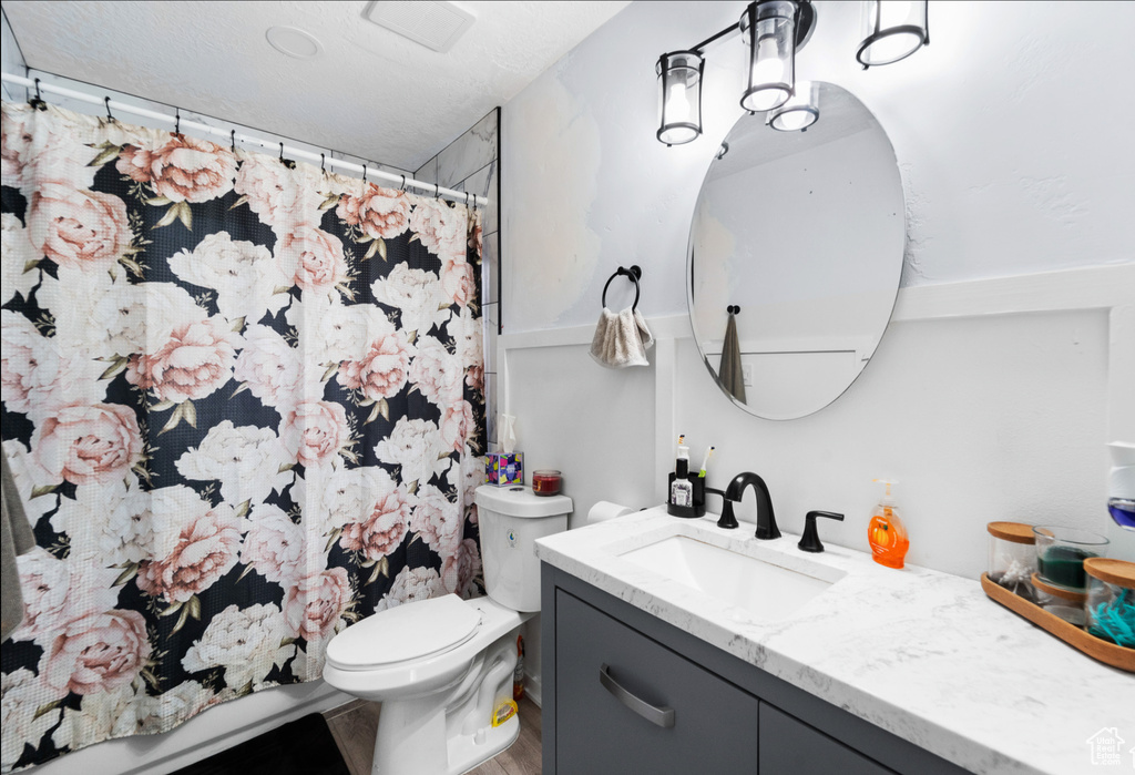 Bathroom featuring vanity, toilet, curtained shower, and wood finished floors