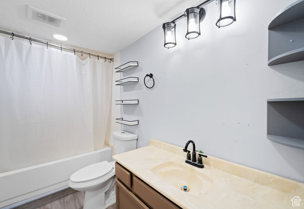 Full bathroom featuring toilet, shower / bathtub combination with curtain, and vanity