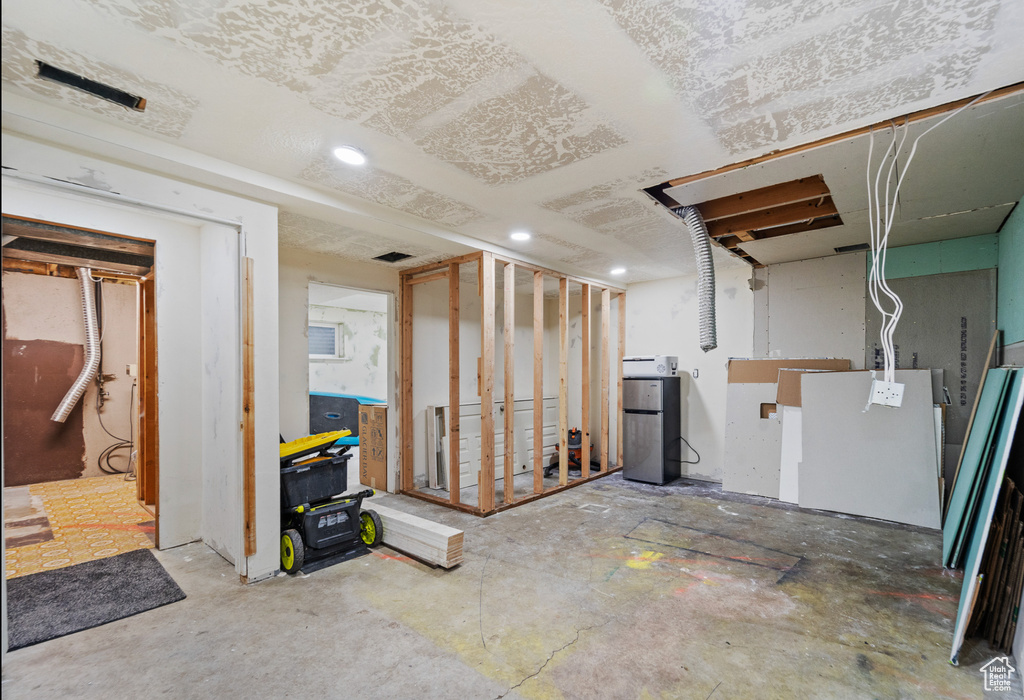 Unfinished below grade area with recessed lighting and freestanding refrigerator