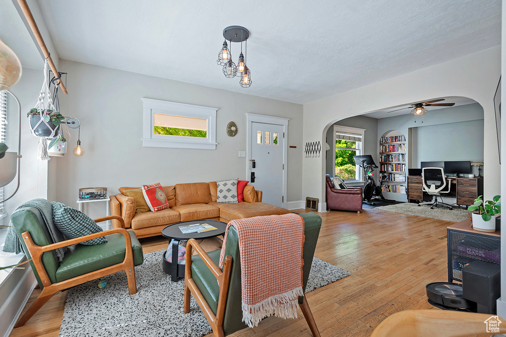 Living room with arched walkways, wood finished floors, ceiling fan, and a desk